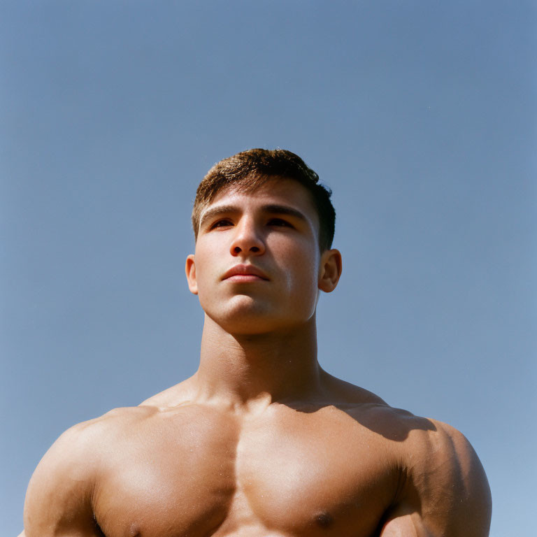 Muscular young man against clear sky horizon.