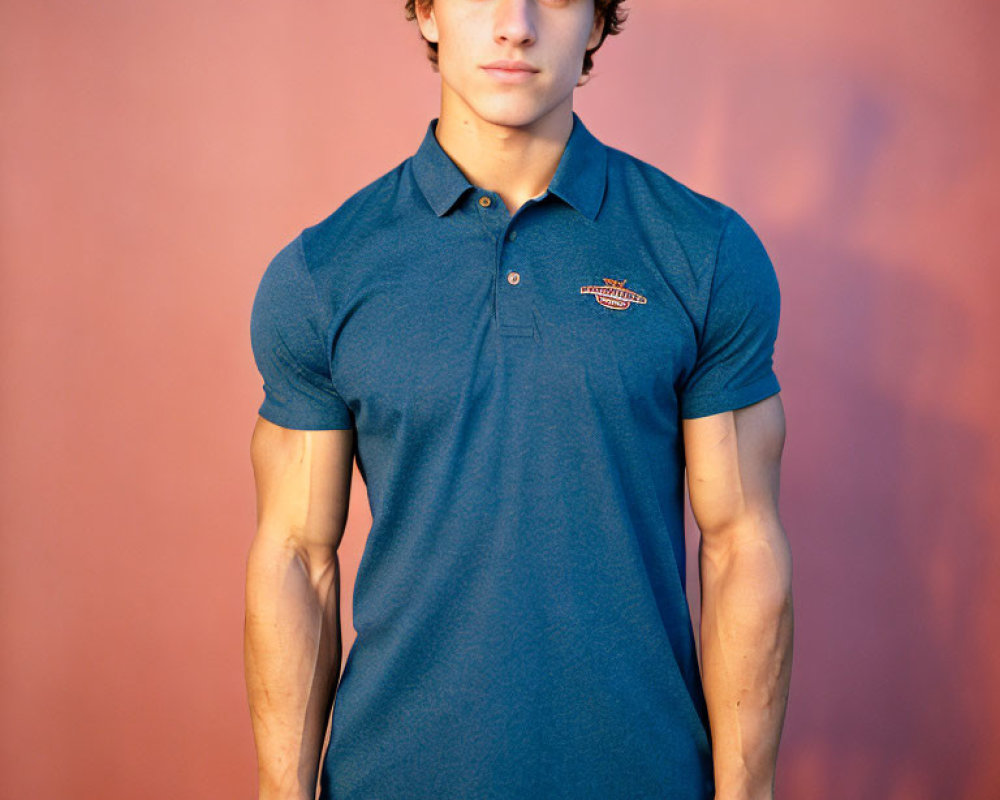 Curly-Haired Young Man in Blue Polo Shirt on Pink Background