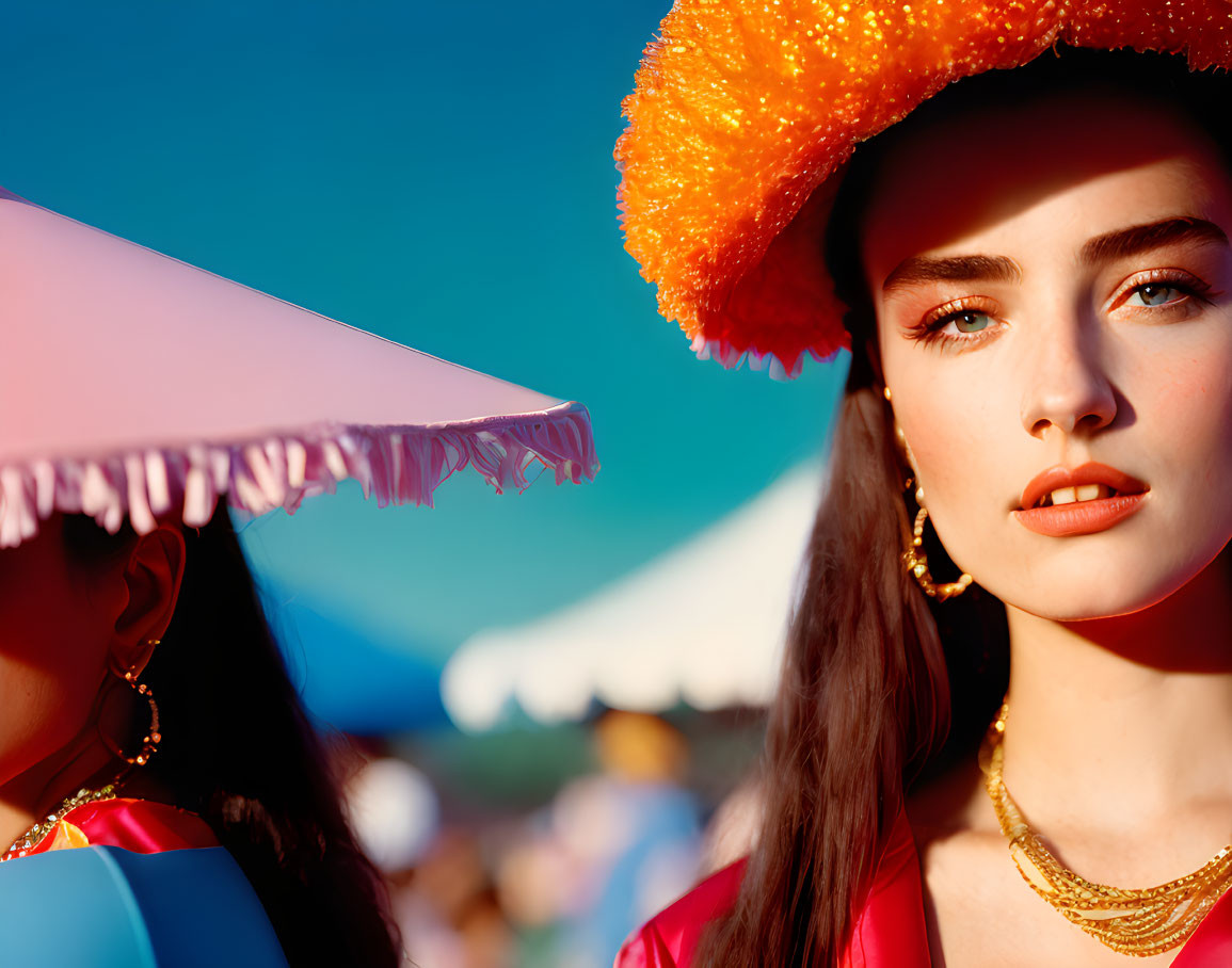 Two women at outdoor event with glittery orange and pink hats.