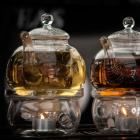 Transparent Teapots with Golden Embellishments and Blooming Tea on Dark Background