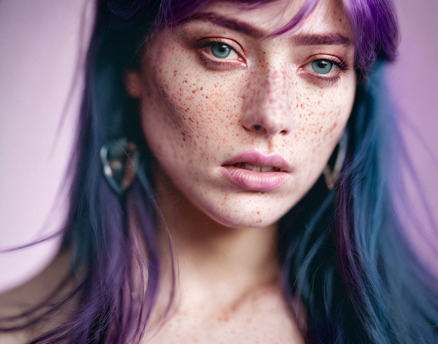 Portrait of person with freckles, blue eyes, and purple hair gazing sideways