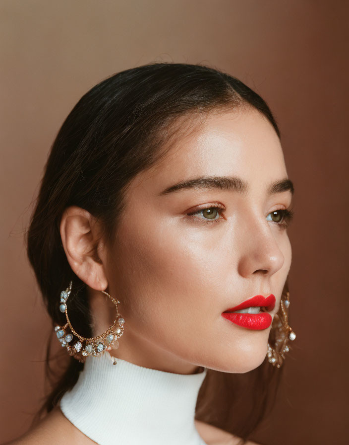 Portrait of Woman with Red Lipstick and Ornate Earrings on Tan Background