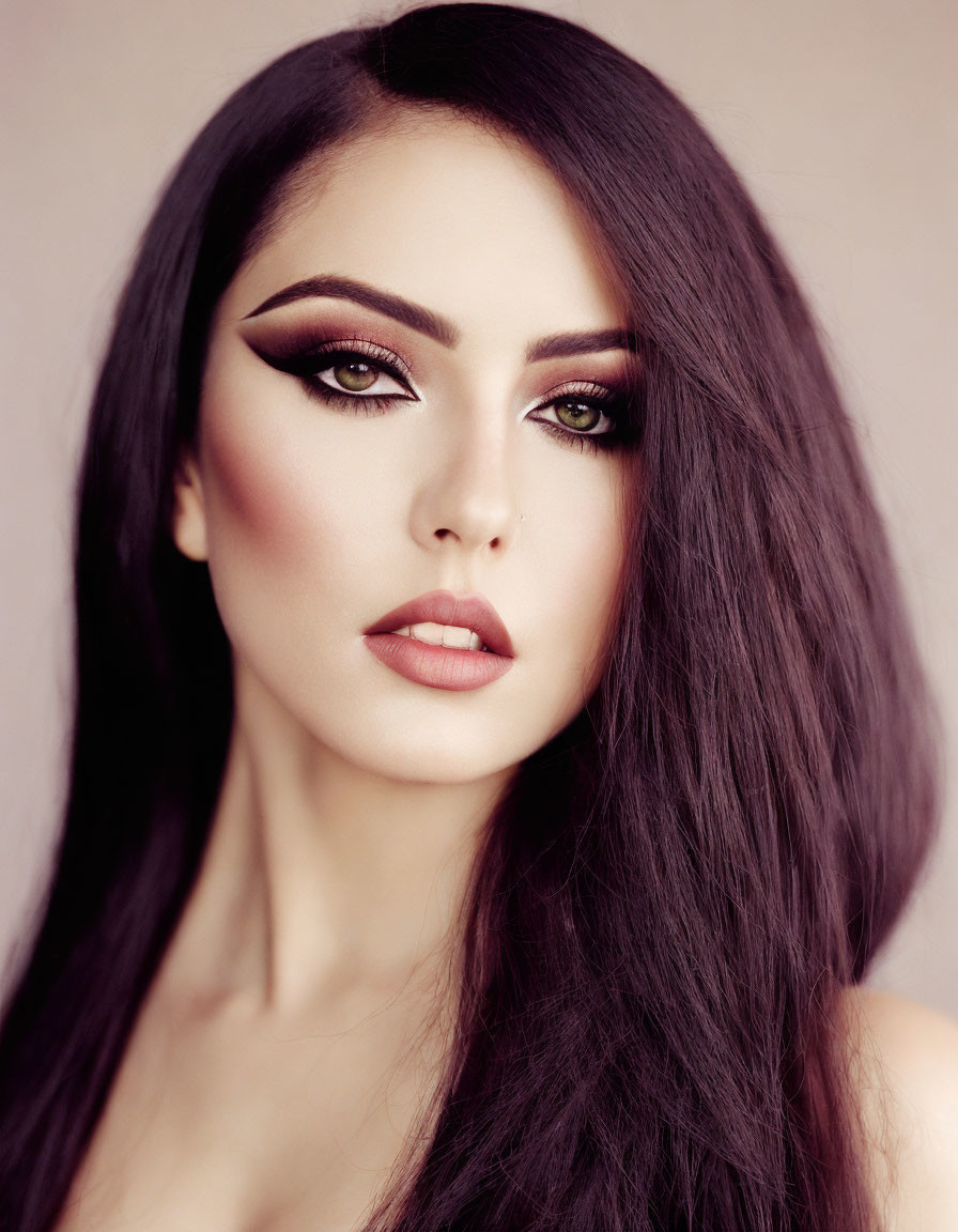 Portrait of woman with long dark hair and bold eyeliner on neutral background