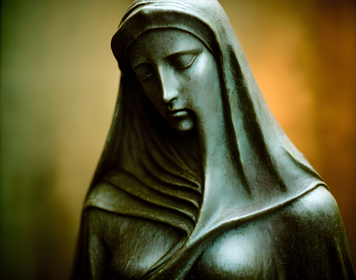 Serene bronze statue of veiled woman against warm background