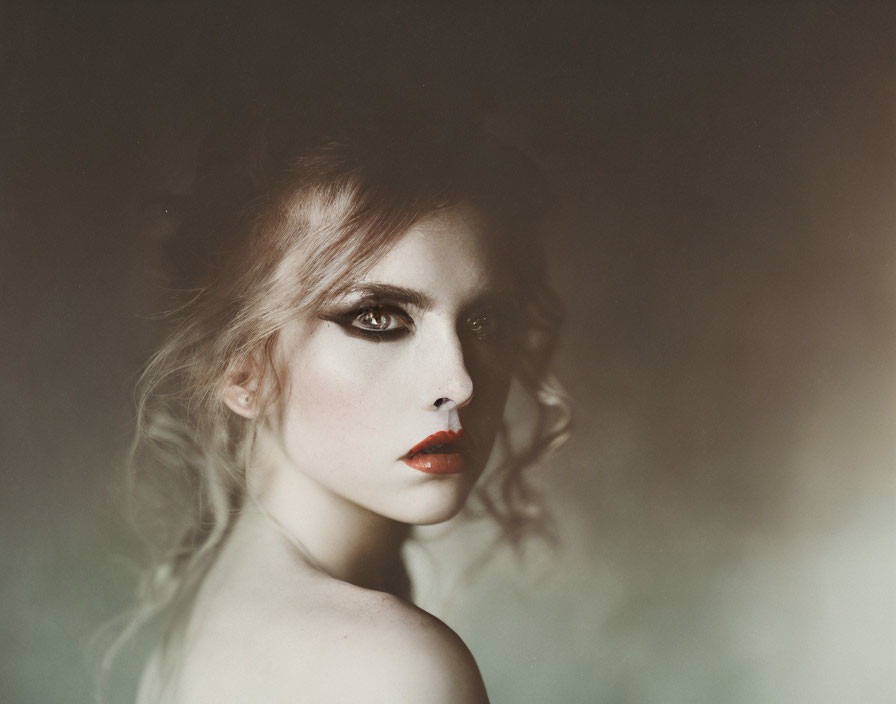 Woman portrait with dramatic makeup: smoky eyes and red lips in dark, hazy setting