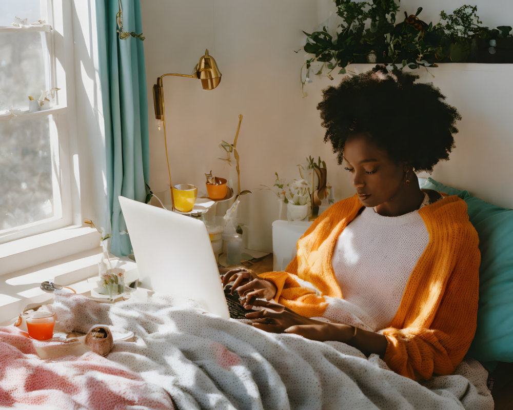 Person in Orange Sweater Using Laptop in Cozy Room with Plants and Soft Light