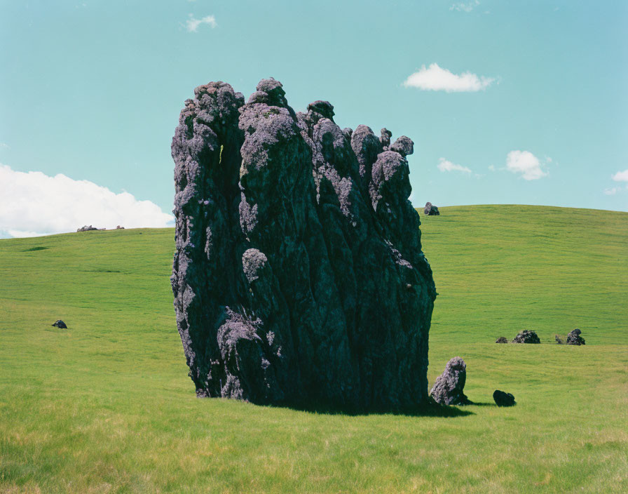 Prominent rugged rock formation on lush green hillside