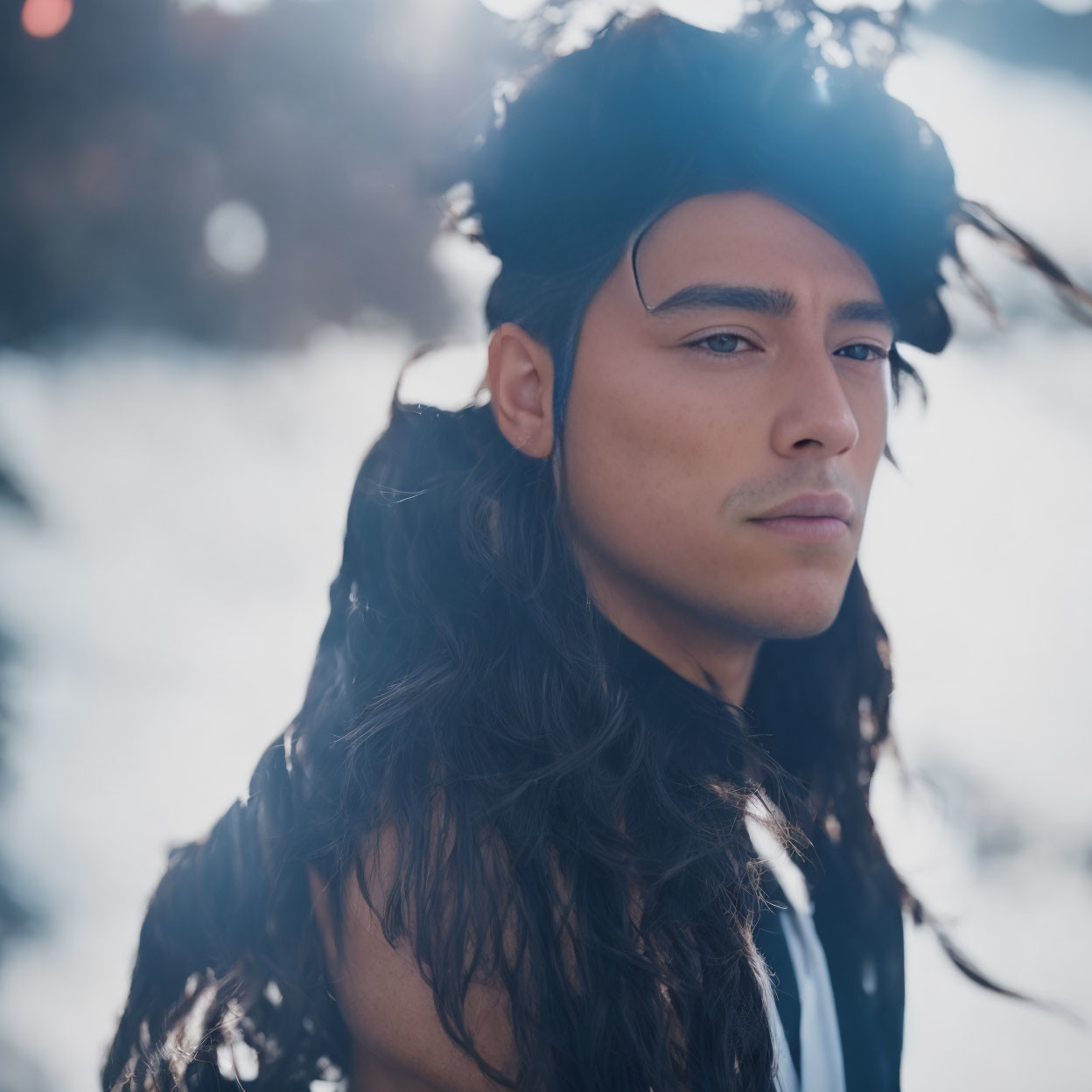 Portrait of a person with long dark hair and headpiece in front of hazy background