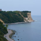 Tranquil seascape with lighthouse, boat, cliffs, and clear sky