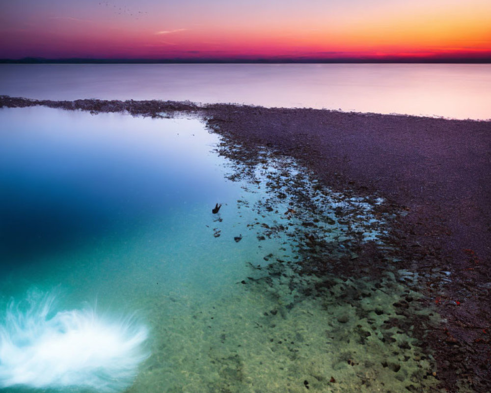 Tranquil lake scene at twilight with rocky shore and submerged plant in clear water