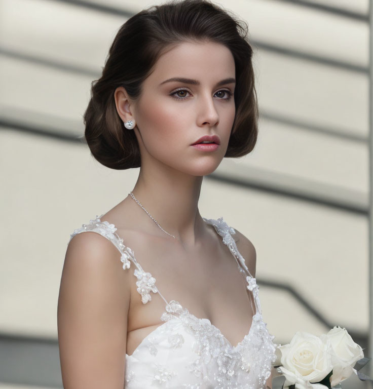 Bridal portrait of woman in white gown with lace details holding white rose bouquet