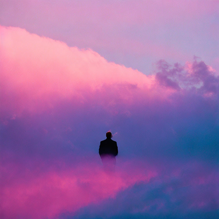 Silhouetted person against vibrant pink and purple sky