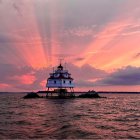 Colorful digital artwork: lighthouse on islet at sunset with purple and pink hues, wavy