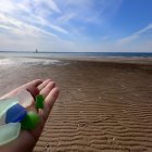 Colorful Translucent Pebbles on Golden Beach Under Blue Sky