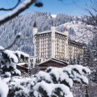 White horses gallop in snow-covered forest with castle and icy peaks