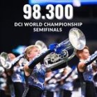 Colorful marching band performs in front of electronic scoreboard displaying "96-200