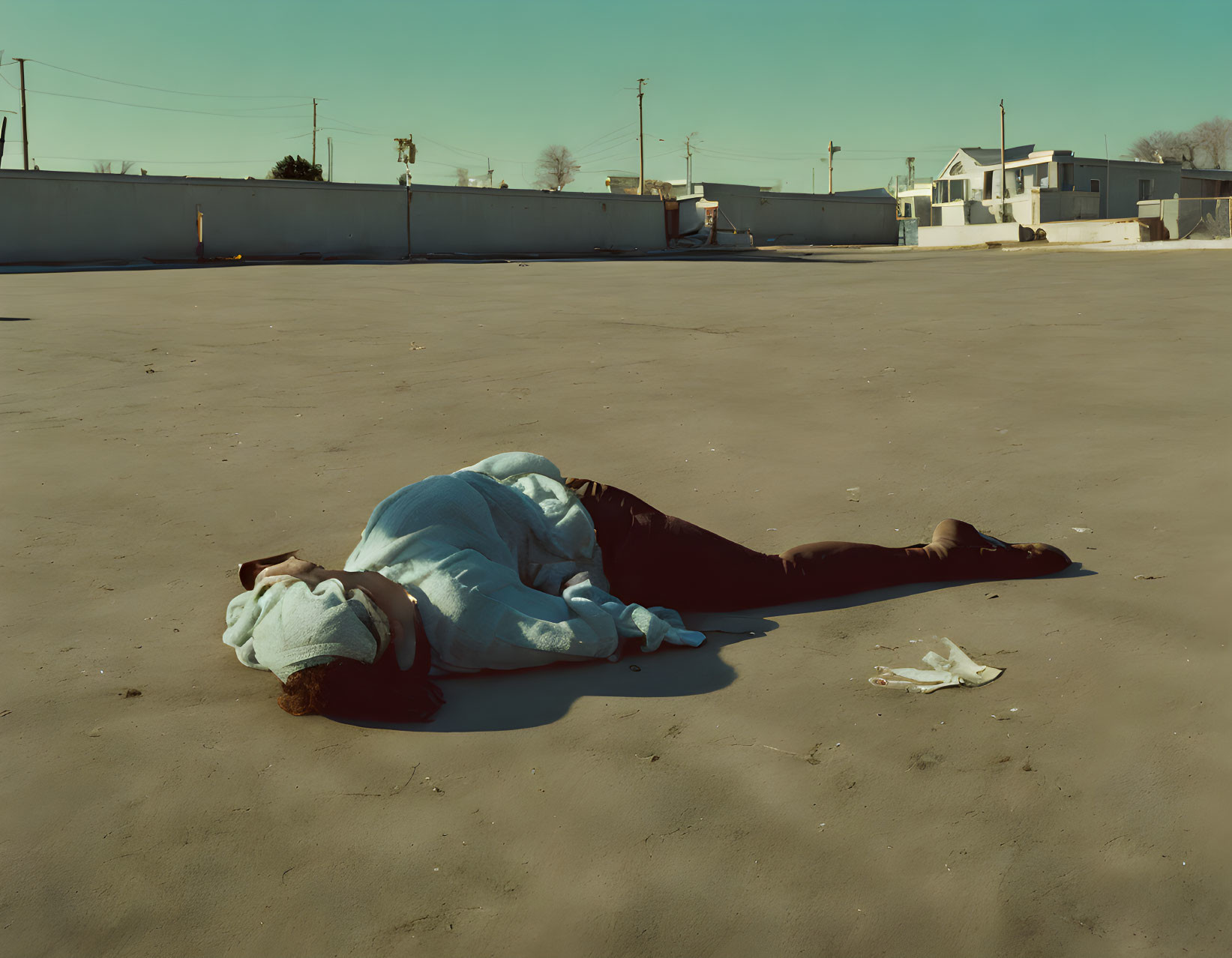 Person in Blue Top and Dark Pants Lying Face Down Outdoors