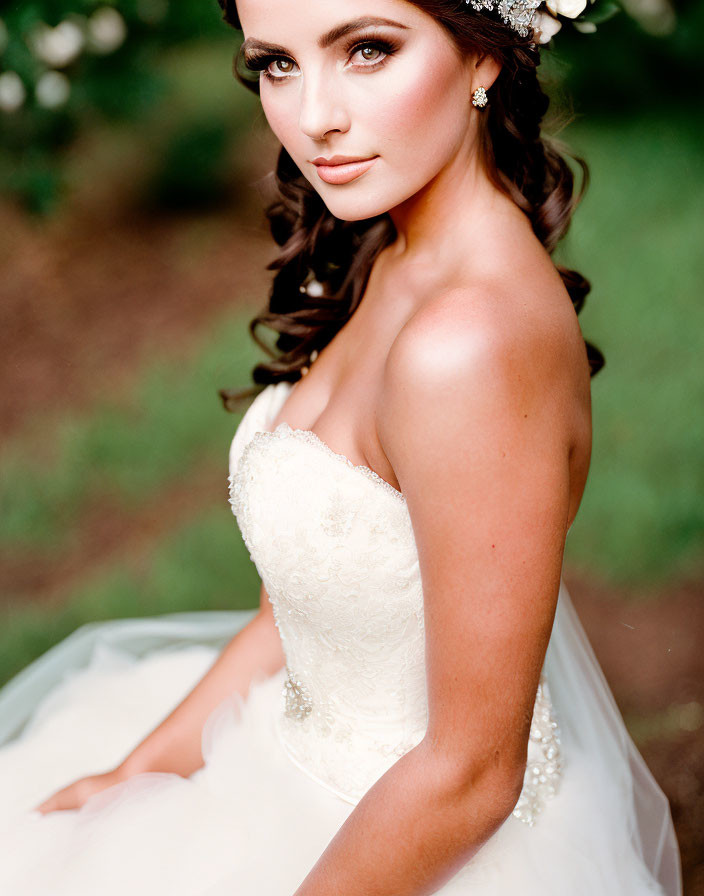 Dark-haired woman in white dress and floral headpiece glances back.