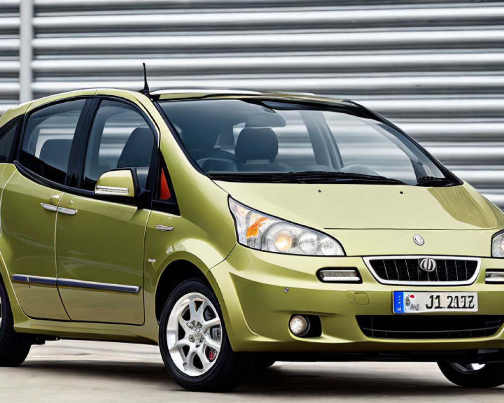 Metallic Olive Green Hatchback Car with Alloy Wheels Parked in Front of Corrugated Metal Background