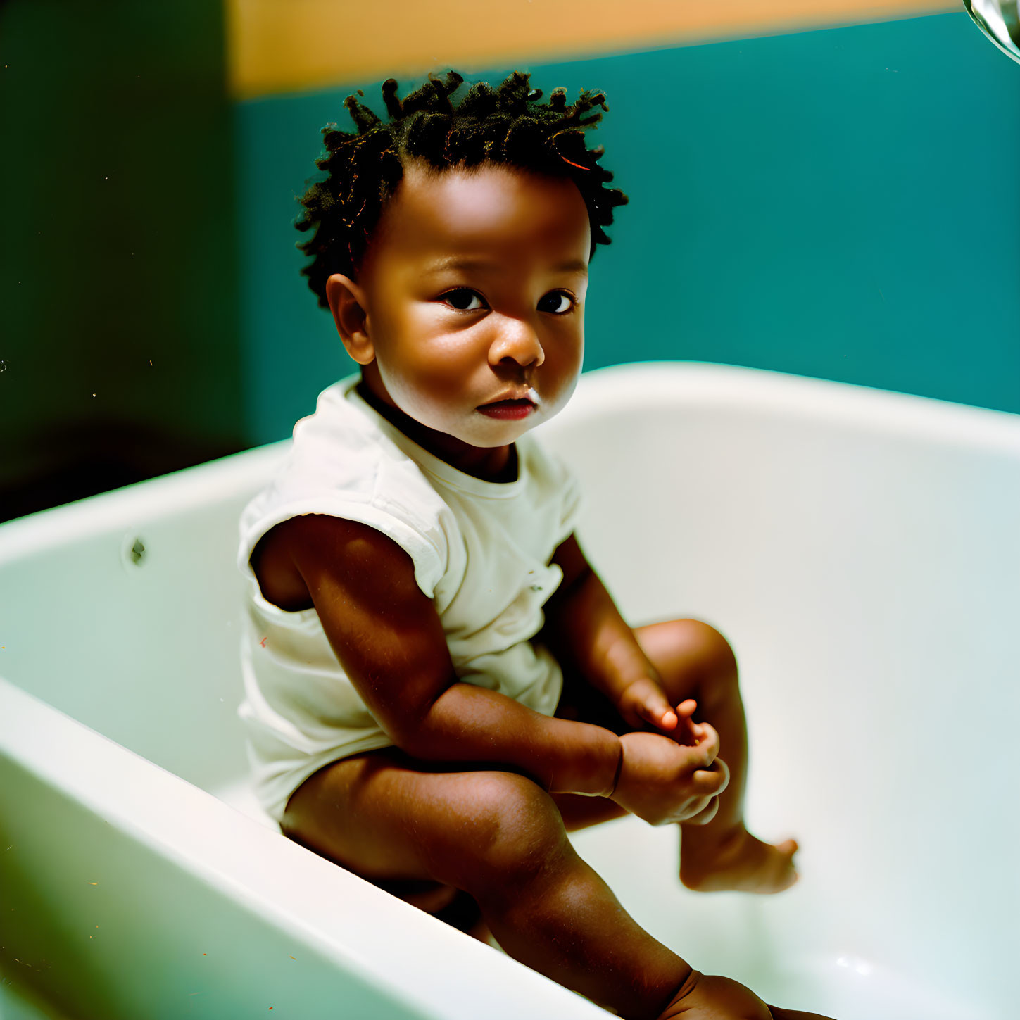 Curly-Haired Toddler in Empty Bathtub with White Top