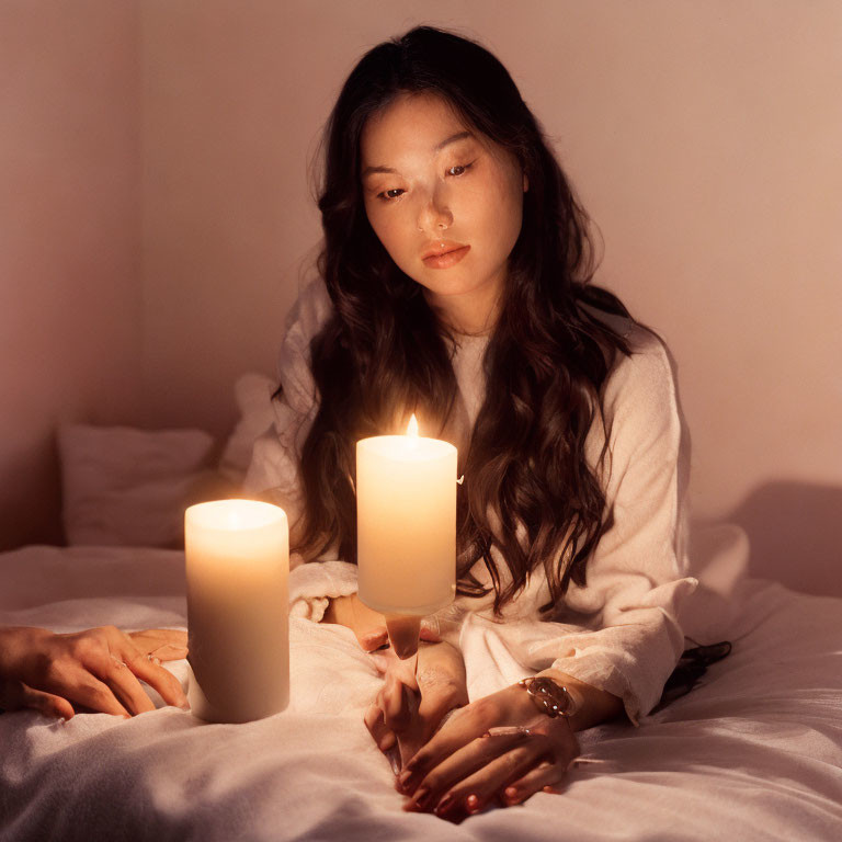 Woman admires lit candles on bed in warm-toned room