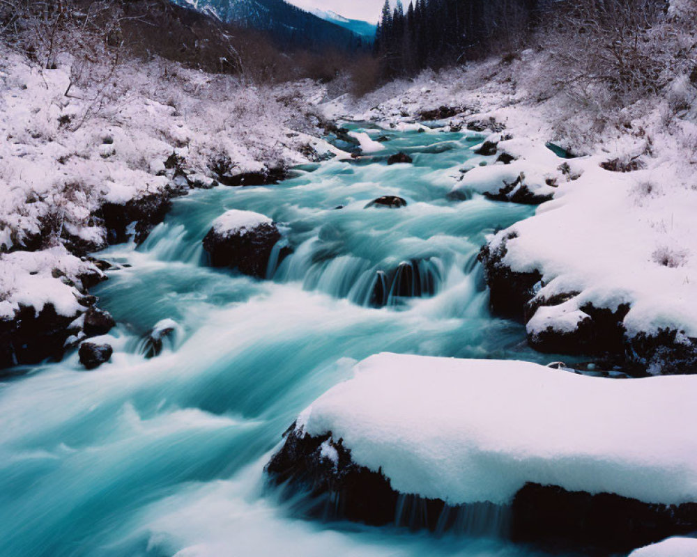 Snow-covered river winding through winter landscape with forested mountains.