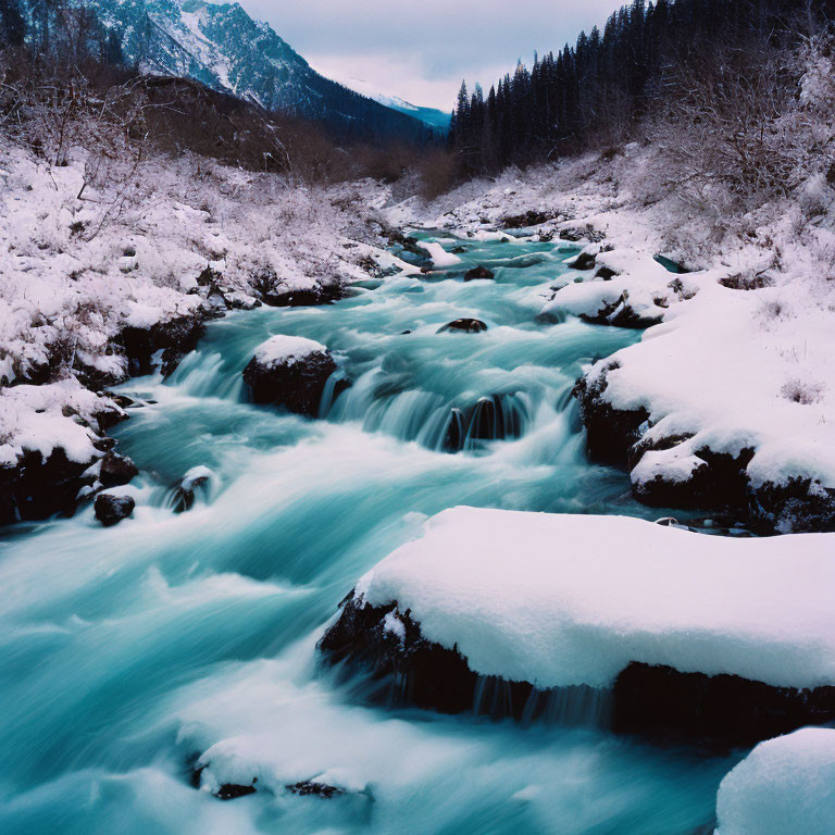 Snow-covered river winding through winter landscape with forested mountains.