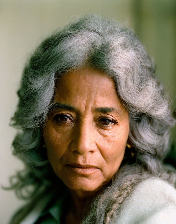 Gray-haired elder woman gazes intensely with wisdom.