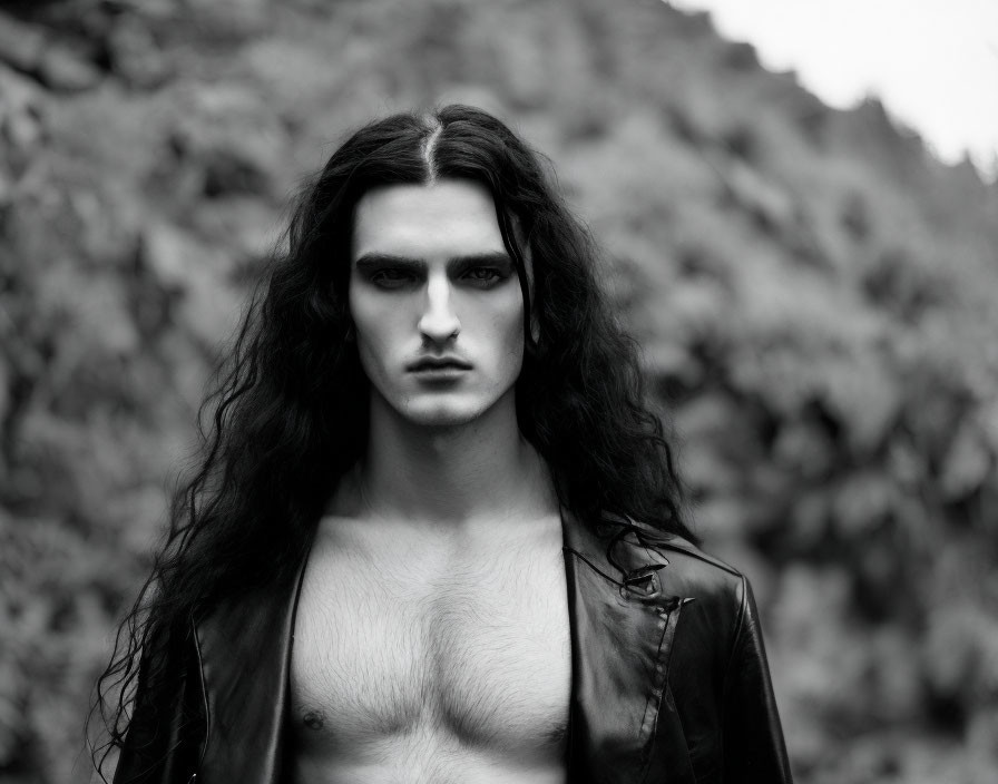 Monochrome portrait of intense-eyed man in leather jacket against nature backdrop