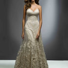 Elegant woman in beige and gold gown with matching accessories on gray backdrop