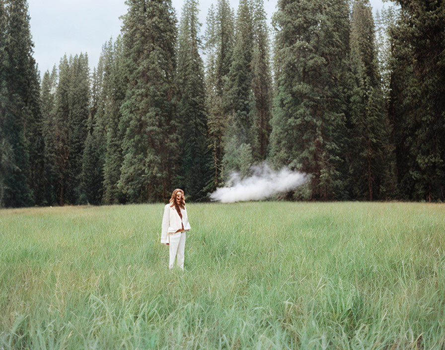 Person in White Attire Standing in Grass Field with Visible Breath Mist