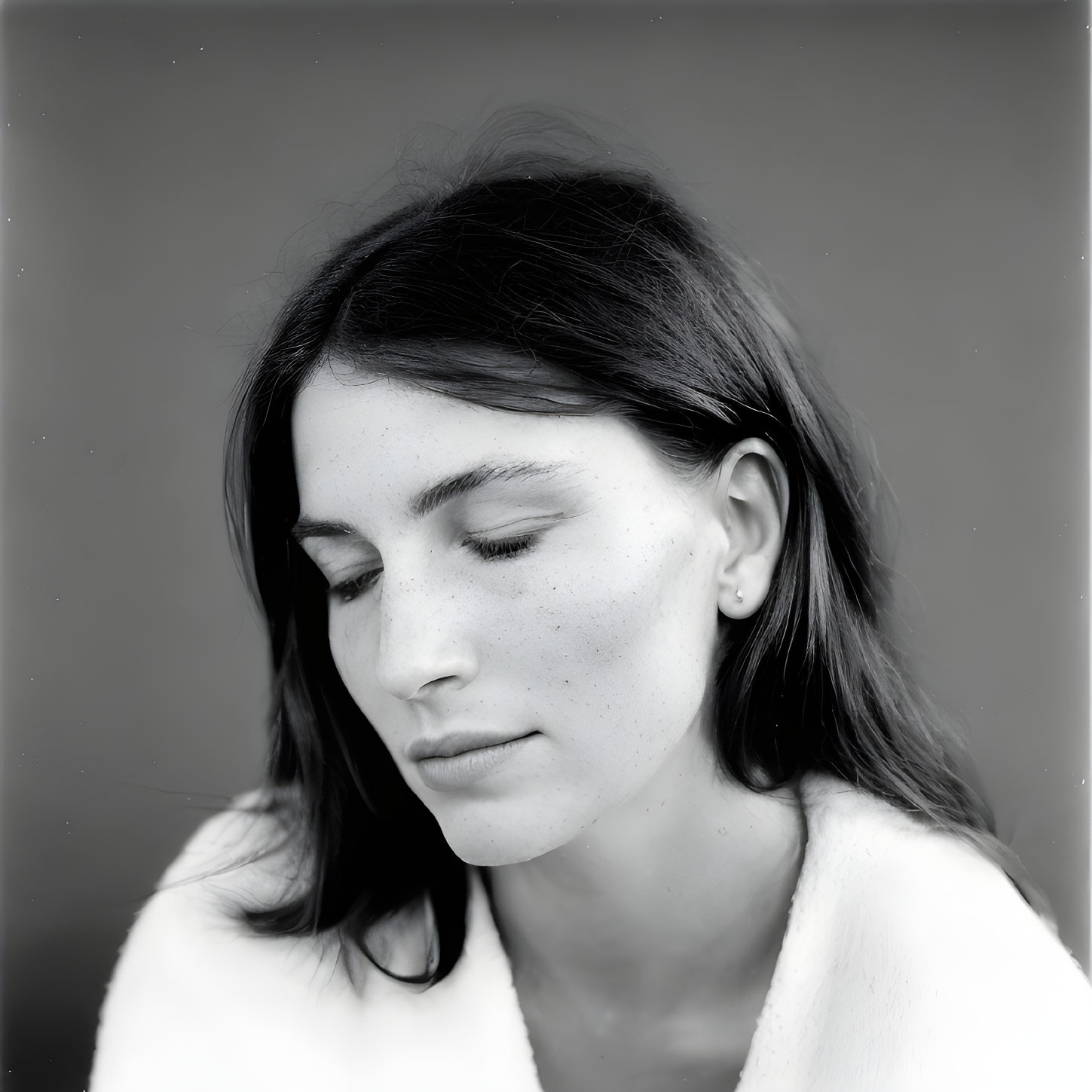 Monochrome portrait of young woman with freckles in contemplative pose