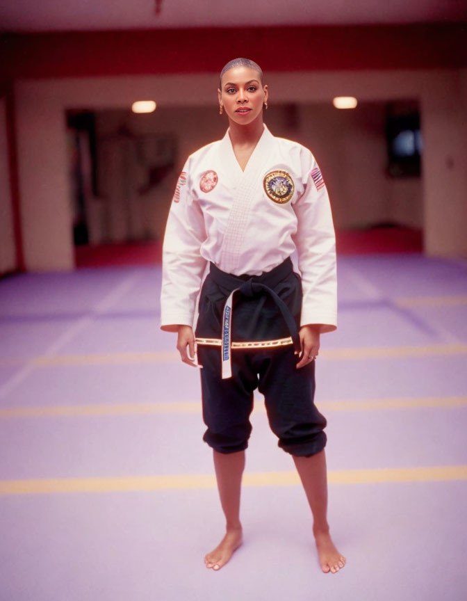 Person in white karate gi with black and red belt on red dojo mat