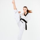 Martial artist in white taekwondo uniform with black belt executing high kick