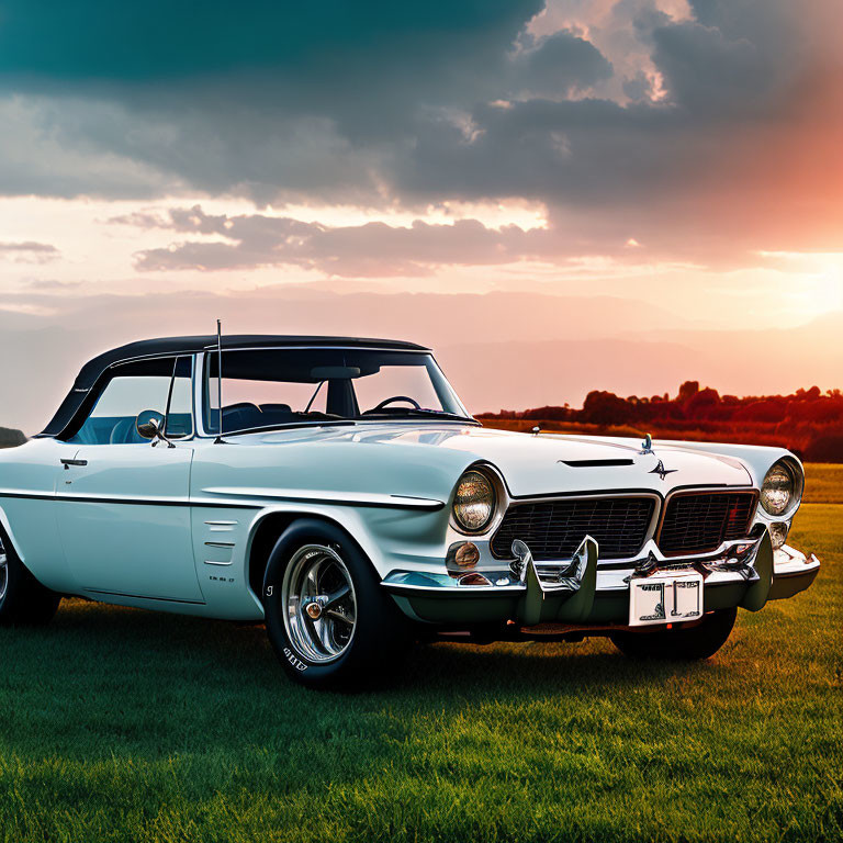 Vintage white convertible car parked on grass under warm sunset sky.