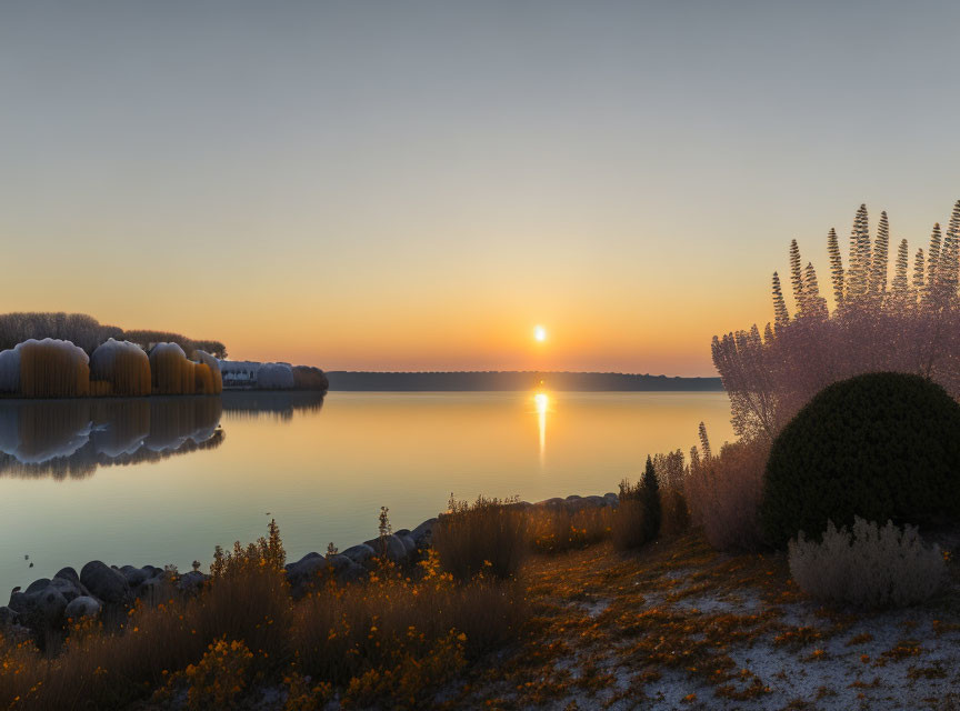 Tranquil sunrise scene over calm lake with autumnal foliage reflections