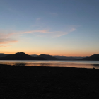 Tranquil sunset over lake with golden hues and silhouetted trees