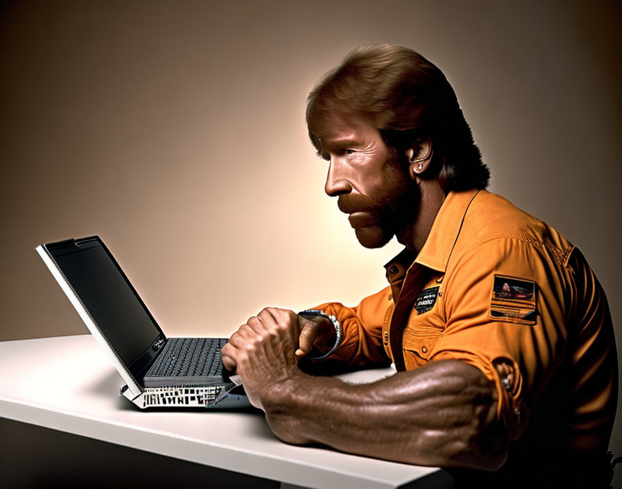 Bearded man in orange shirt at white desk with laptop