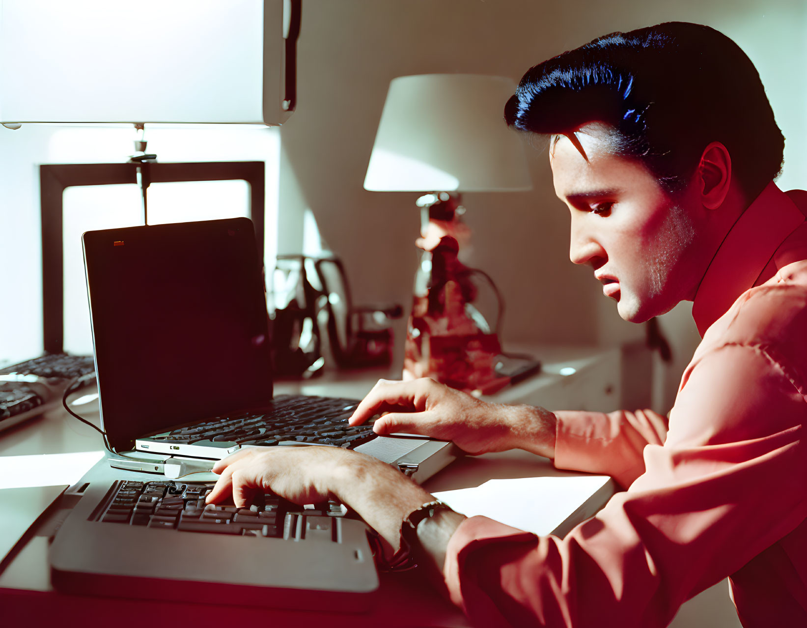 Dark-haired man on laptop in warmly lit room