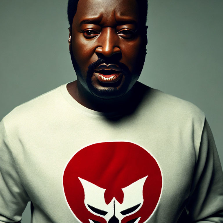 Bearded man in grey sweatshirt with red and white logo on grey background