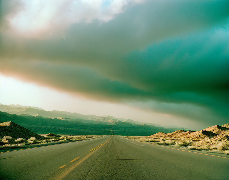 Deserted highway under dramatic sky with dark clouds.