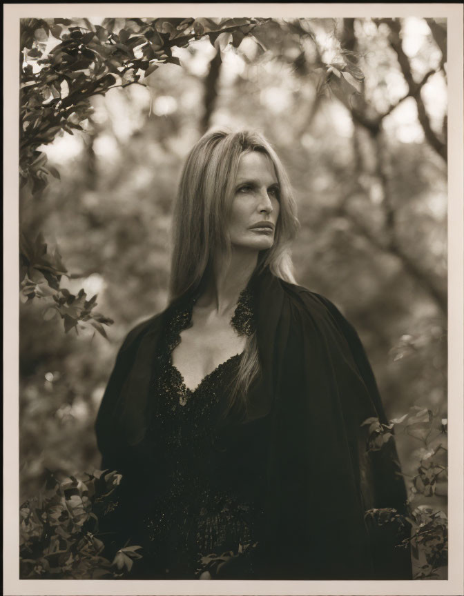 Long-haired woman in dark gown among trees, gazing sideways