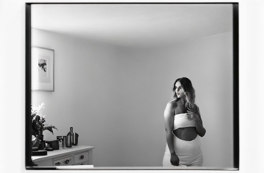 Monochrome image of woman at vanity with plants and bottles