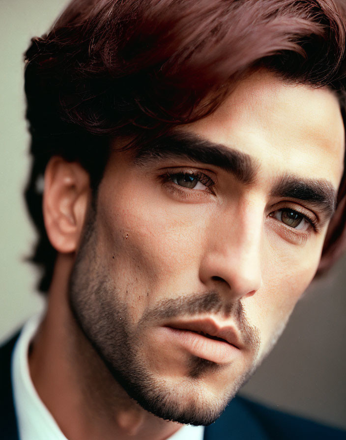 Portrait of a man with dark hair, bold brows, beard, and suit.