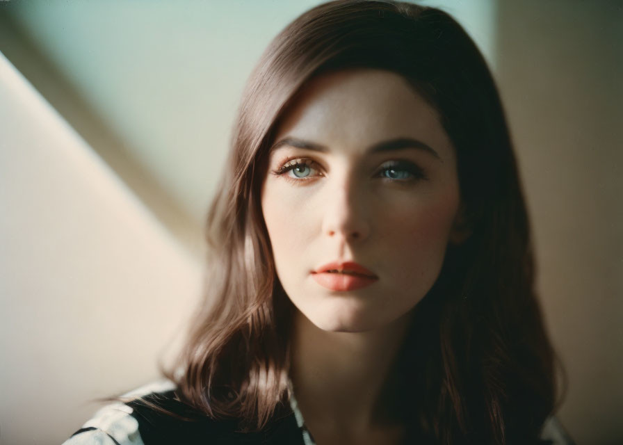 Brown-haired woman with blue eyes in soft lighting, gazing sideways