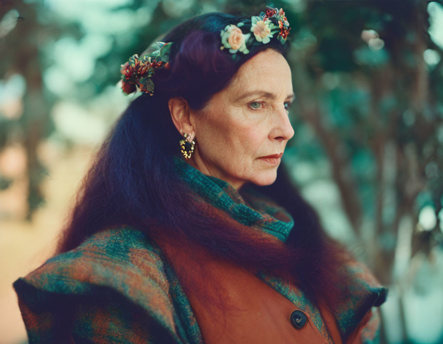 Woman wearing floral crown and red scarf with brown hair and earrings.