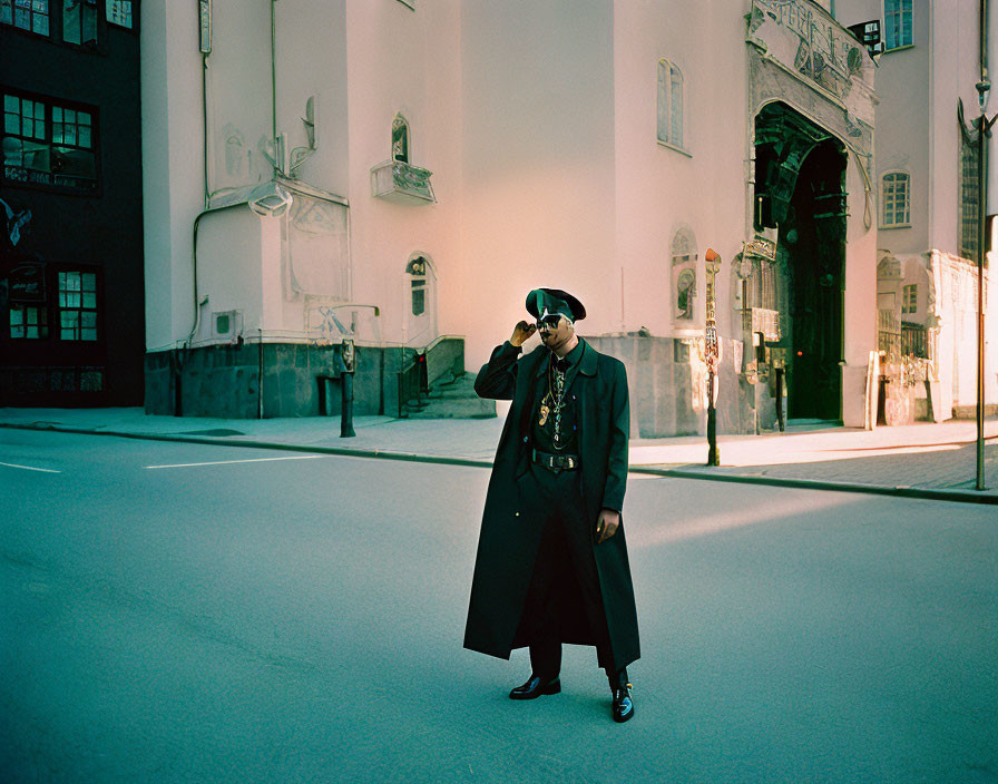 Person in Black Coat and Hat on Deserted Street with Ornate Buildings