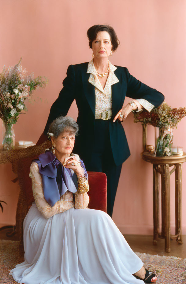 Elegantly dressed women posing confidently in pink backdrop room