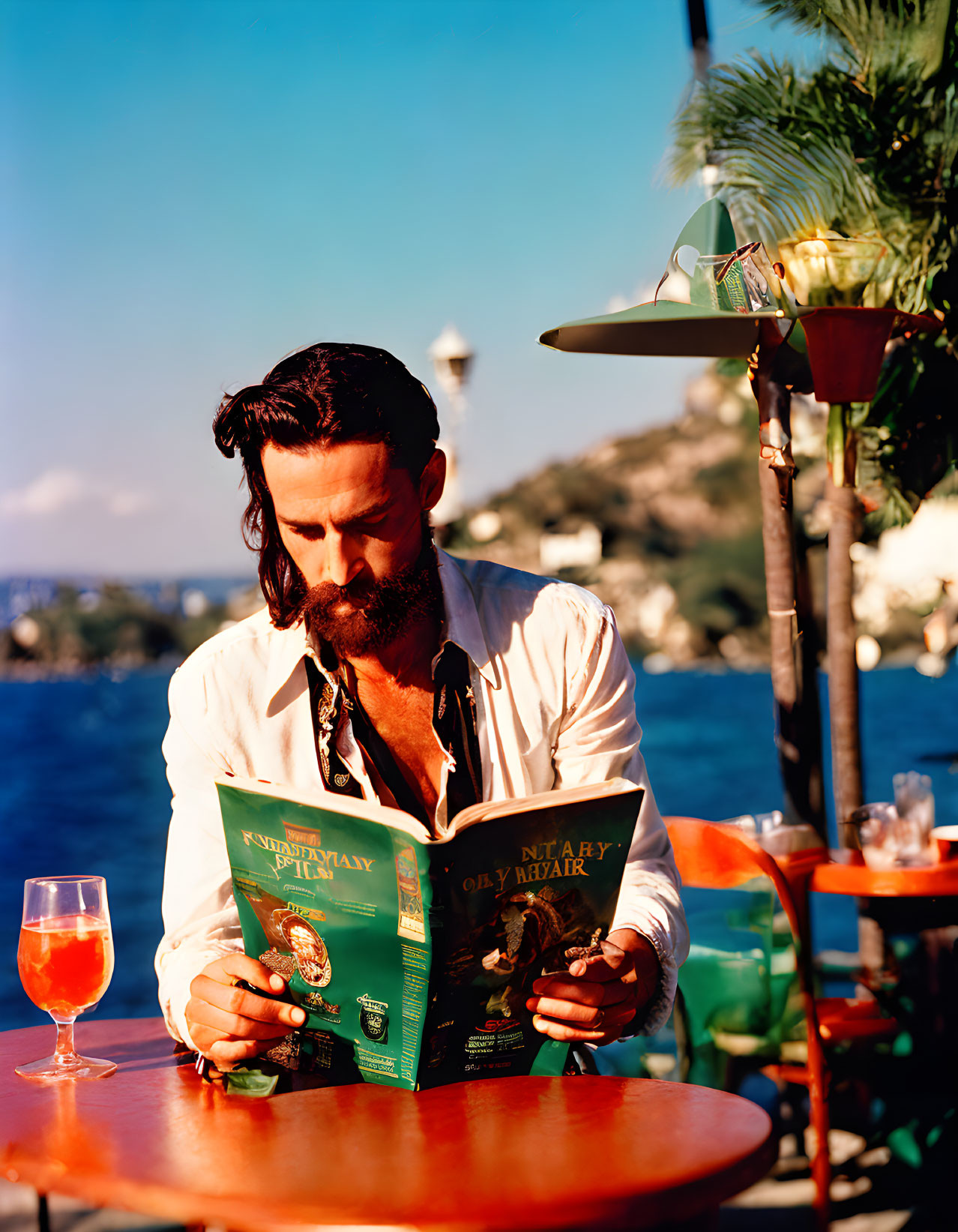 Bearded man reading menu at seaside restaurant with ocean view