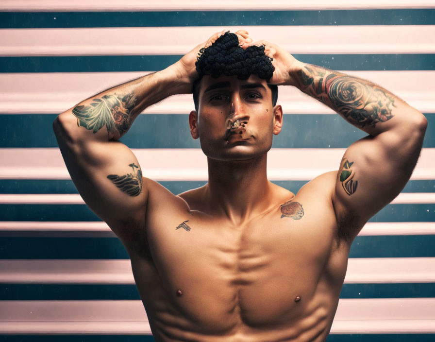 Tattooed man with undercut hairstyle poses shirtless on striped background